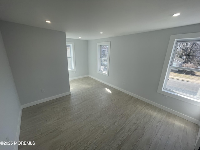 spare room with dark wood finished floors, recessed lighting, baseboards, and a wealth of natural light