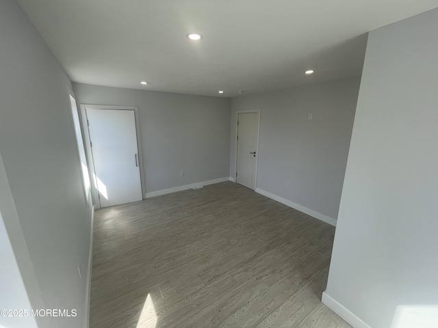 empty room with recessed lighting, light wood-type flooring, and baseboards