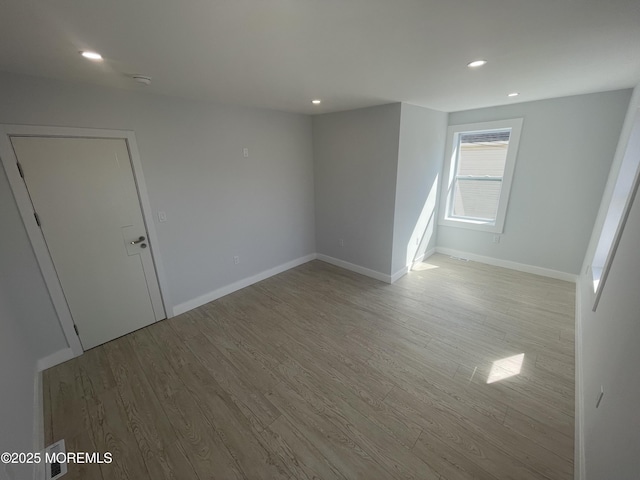 unfurnished room with recessed lighting, wood finished floors, and baseboards