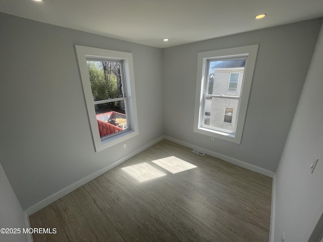 spare room with recessed lighting, baseboards, and wood finished floors