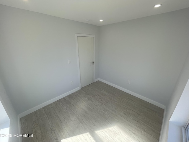 spare room with recessed lighting, baseboards, and wood finished floors