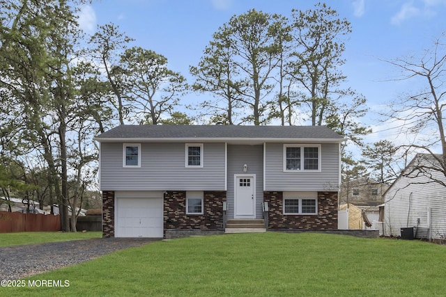 bi-level home with central AC, brick siding, a front lawn, and fence