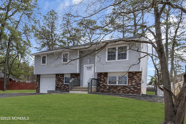 split foyer home featuring an attached garage, driveway, a front lawn, and brick siding