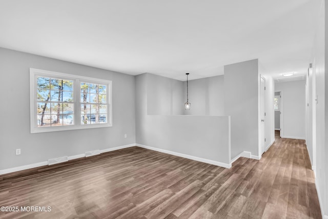 spare room with visible vents, baseboards, and wood finished floors