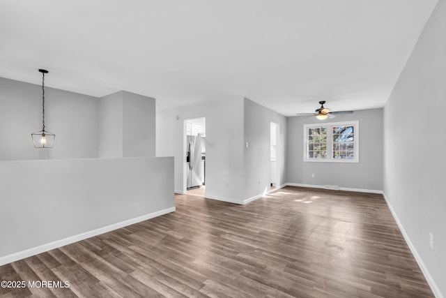 empty room featuring visible vents, wood finished floors, a ceiling fan, and baseboards