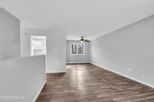 empty room featuring ceiling fan, baseboards, and dark wood finished floors