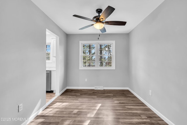 empty room with baseboards, visible vents, ceiling fan, and wood finished floors