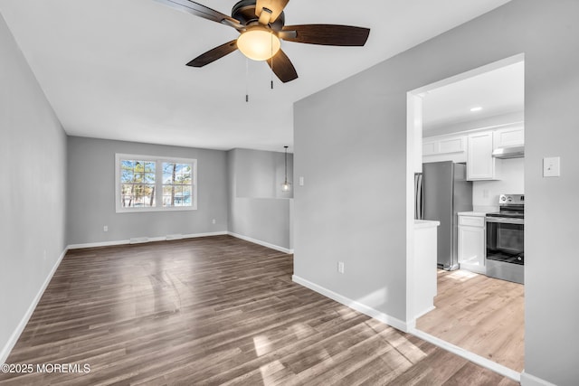 unfurnished living room featuring ceiling fan, baseboards, and wood finished floors