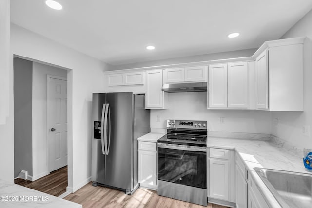 kitchen with stainless steel appliances, light wood-style floors, white cabinets, a sink, and under cabinet range hood