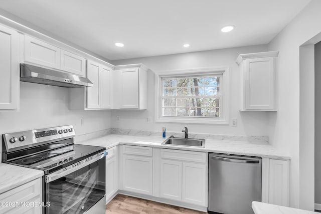 kitchen featuring appliances with stainless steel finishes, under cabinet range hood, white cabinetry, a sink, and recessed lighting