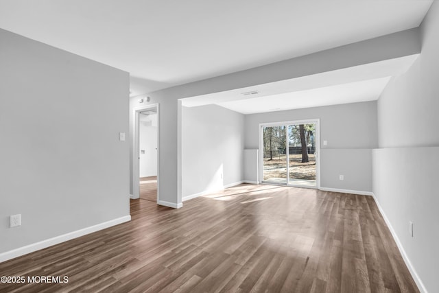 spare room featuring wood finished floors, visible vents, and baseboards