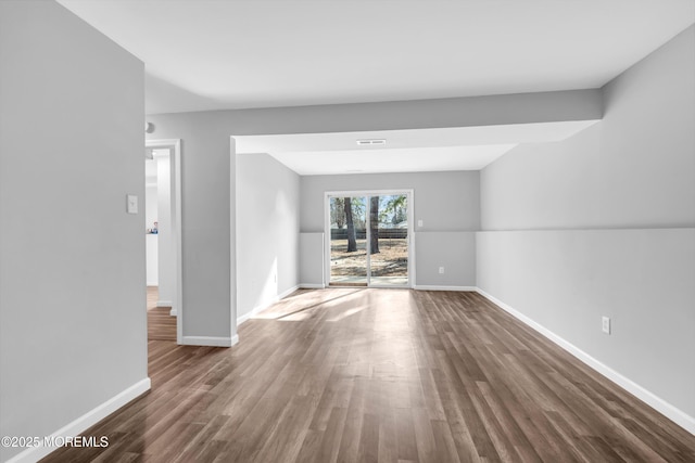 unfurnished living room featuring wood finished floors, visible vents, and baseboards