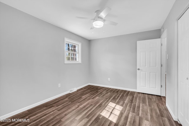 unfurnished bedroom with dark wood-style flooring, a closet, visible vents, ceiling fan, and baseboards