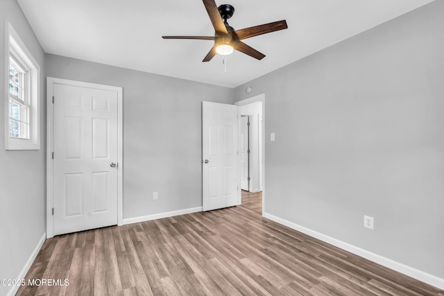 unfurnished bedroom featuring ceiling fan, baseboards, and wood finished floors