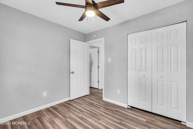 unfurnished bedroom featuring ceiling fan, a closet, wood finished floors, and baseboards