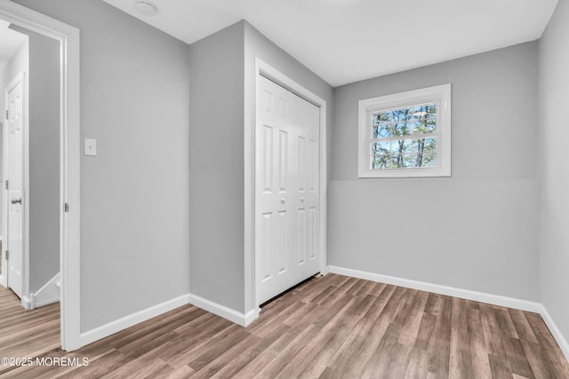 unfurnished bedroom featuring a closet, baseboards, and wood finished floors