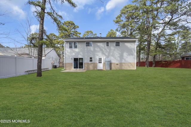 back of house with a fenced backyard and a lawn