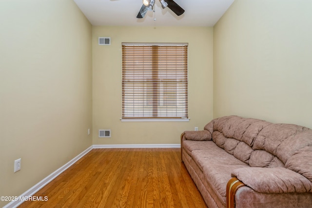 living area with light wood-type flooring, visible vents, and baseboards