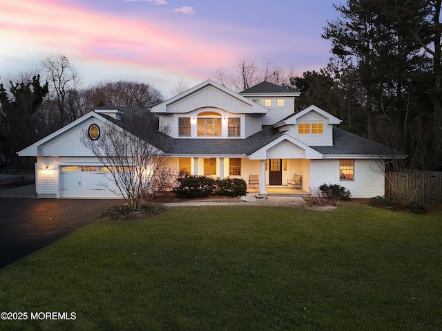 view of front facade with a garage, a front lawn, aphalt driveway, and roof with shingles