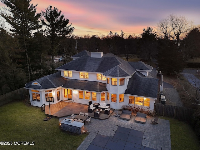 back of property with a lawn, a patio, an outdoor living space with a fire pit, fence, and a deck