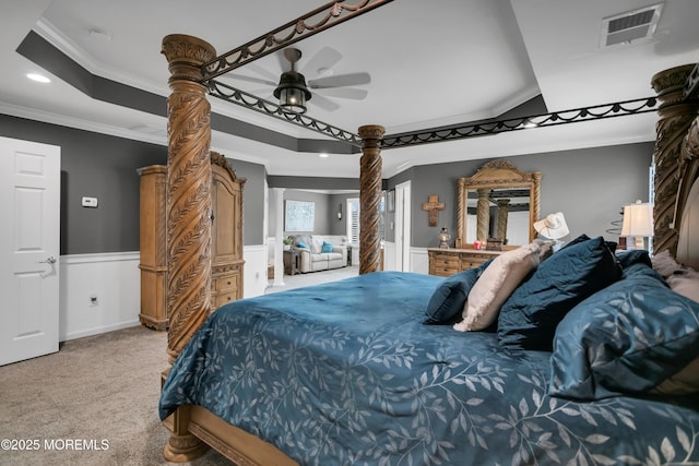 carpeted bedroom featuring a tray ceiling, crown molding, recessed lighting, visible vents, and wainscoting