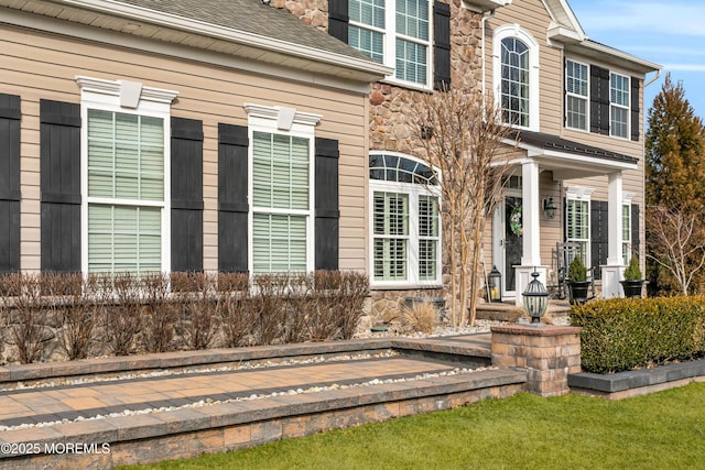 doorway to property with stone siding and roof with shingles