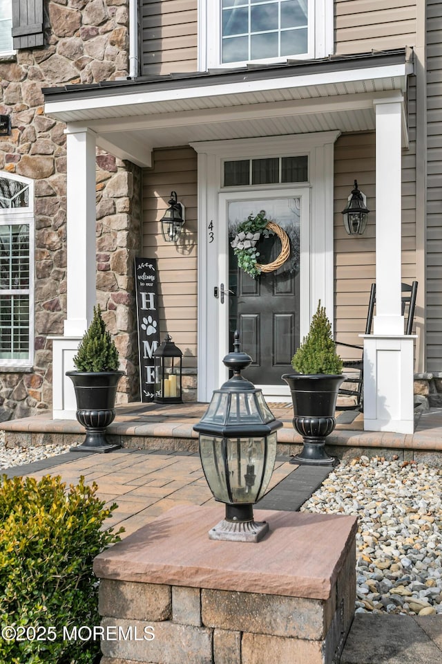 property entrance featuring a porch and stone siding