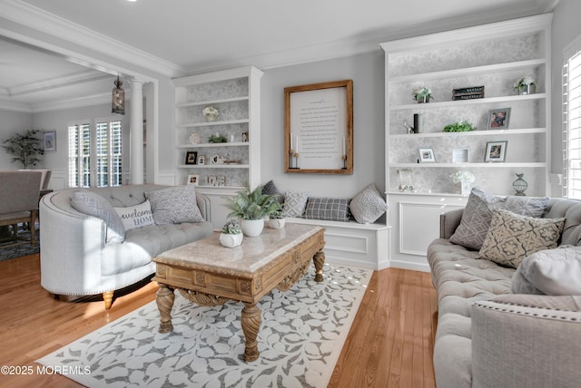 living room with built in shelves, wood finished floors, and crown molding