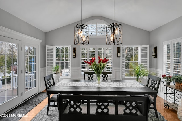 dining area featuring lofted ceiling, wainscoting, and wood finished floors