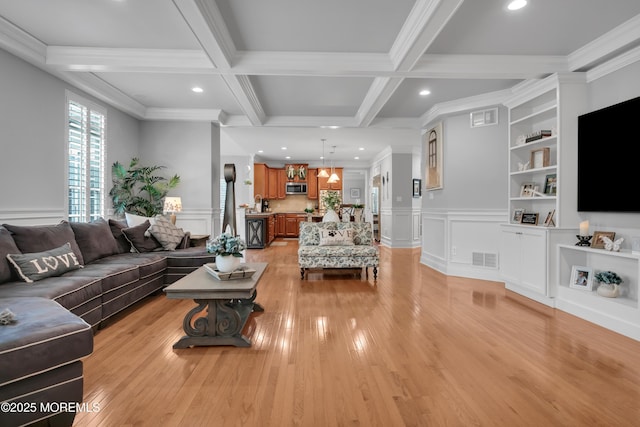 living room with visible vents, coffered ceiling, crown molding, light wood-type flooring, and beam ceiling