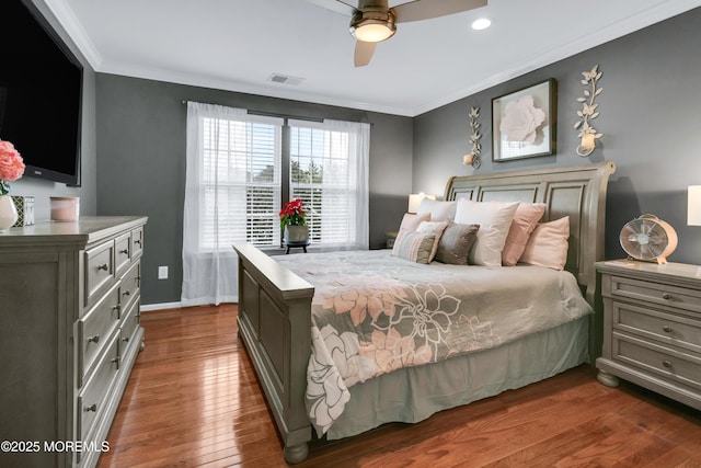 bedroom with visible vents, ornamental molding, a ceiling fan, wood finished floors, and baseboards