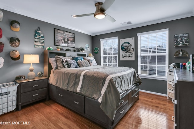 bedroom featuring ornamental molding, wood finished floors, visible vents, and baseboards