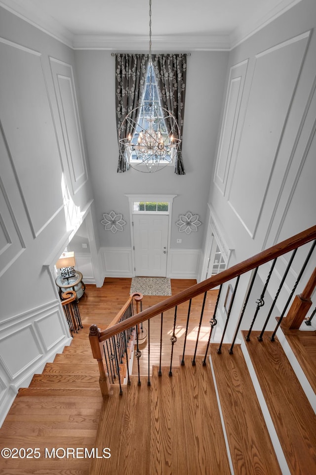 stairway with crown molding, a decorative wall, and wood finished floors