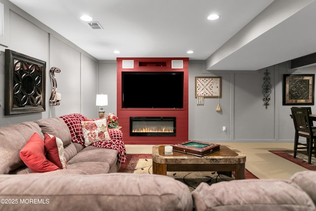 carpeted living room with a large fireplace, visible vents, a decorative wall, and recessed lighting