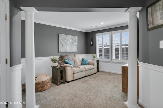 carpeted living area with a wainscoted wall, decorative columns, and crown molding