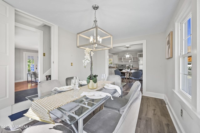 dining room featuring dark wood-type flooring, baseboards, and an inviting chandelier