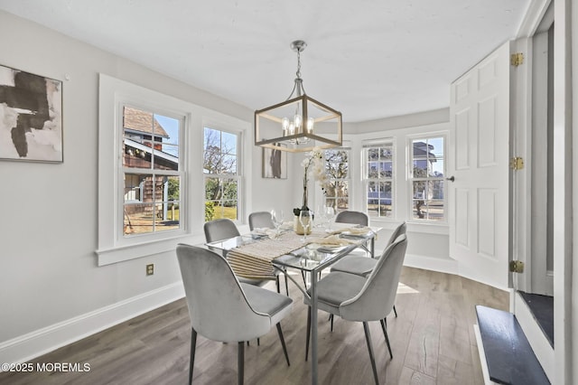 dining area with dark wood-style floors, a notable chandelier, and baseboards