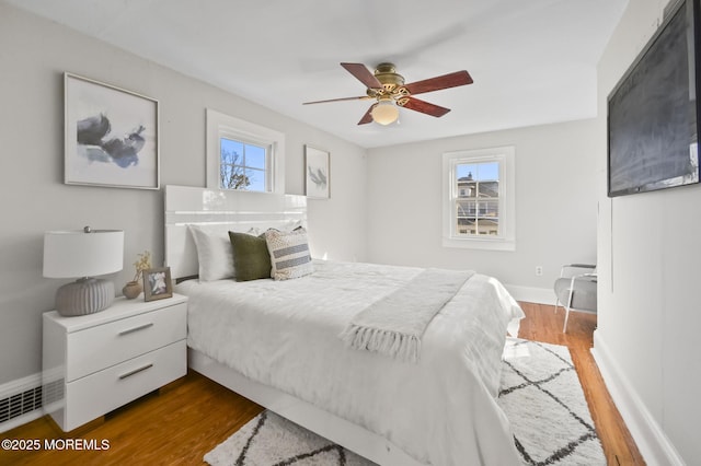 bedroom with dark wood-style floors, baseboards, and a ceiling fan