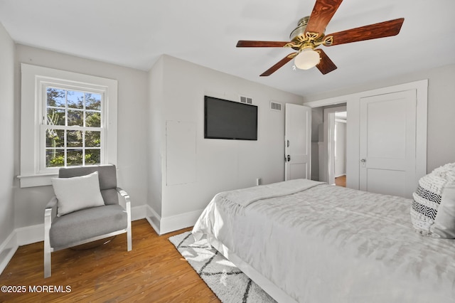 bedroom featuring baseboards, ceiling fan, visible vents, and light wood-style floors