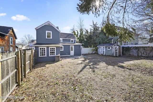 rear view of house with a fenced backyard, a shed, and an outdoor structure