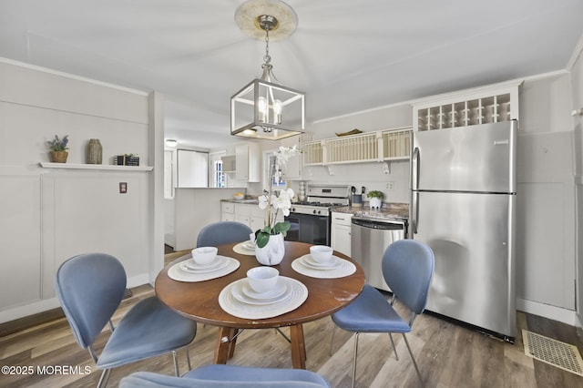 dining room featuring a chandelier, visible vents, crown molding, and wood finished floors