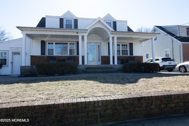 bungalow-style house with a porch, a front yard, and brick siding