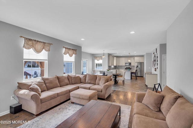 living area with baseboards, wood finished floors, and recessed lighting