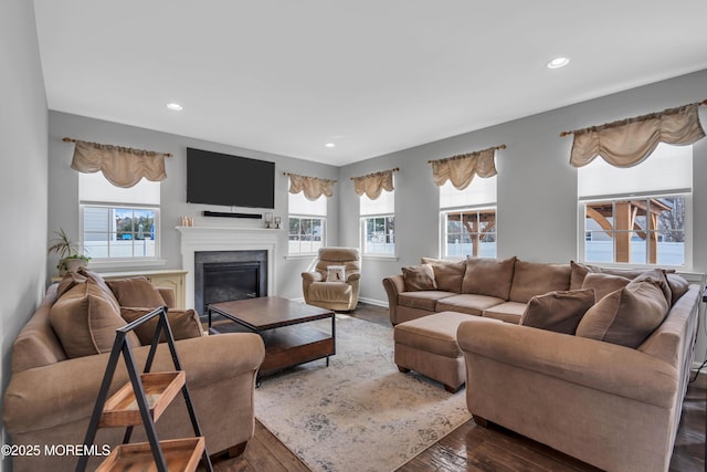 living room featuring baseboards, dark wood-type flooring, a glass covered fireplace, and recessed lighting