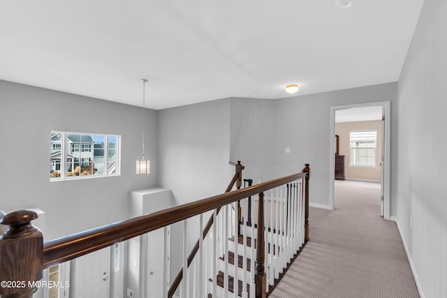 hallway with baseboards, light carpet, and an upstairs landing