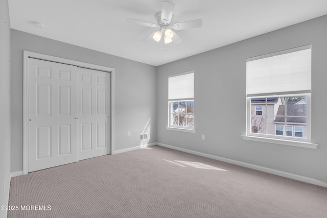 unfurnished bedroom featuring baseboards, a closet, and light colored carpet