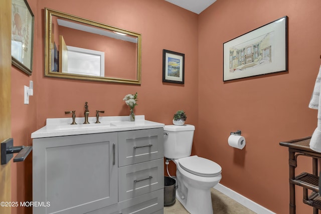 half bathroom with vanity, toilet, and baseboards