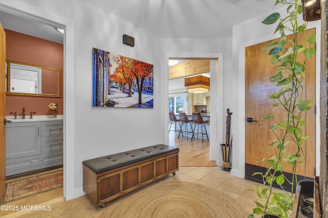 hallway featuring tile patterned floors, baseboards, and a sink