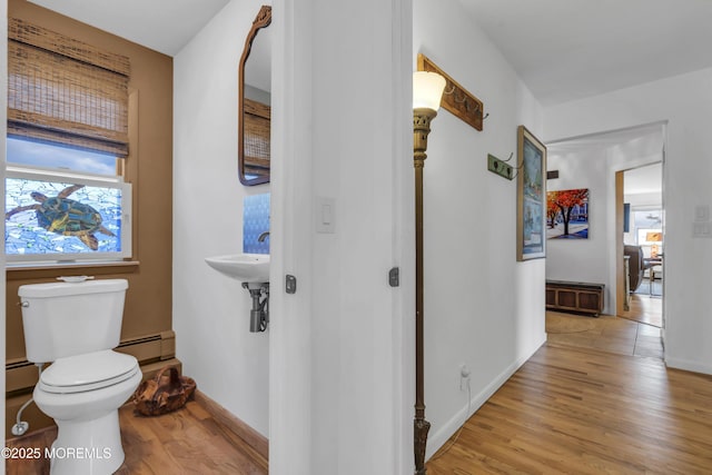 hallway featuring light wood-type flooring, a baseboard radiator, and baseboards