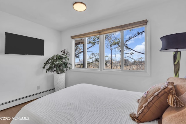 bedroom with a baseboard heating unit and wood finished floors